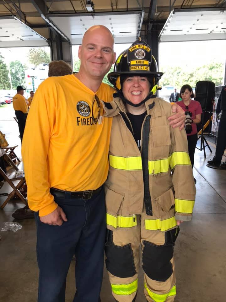 A man and woman in fireman 's gear posing for the camera.
